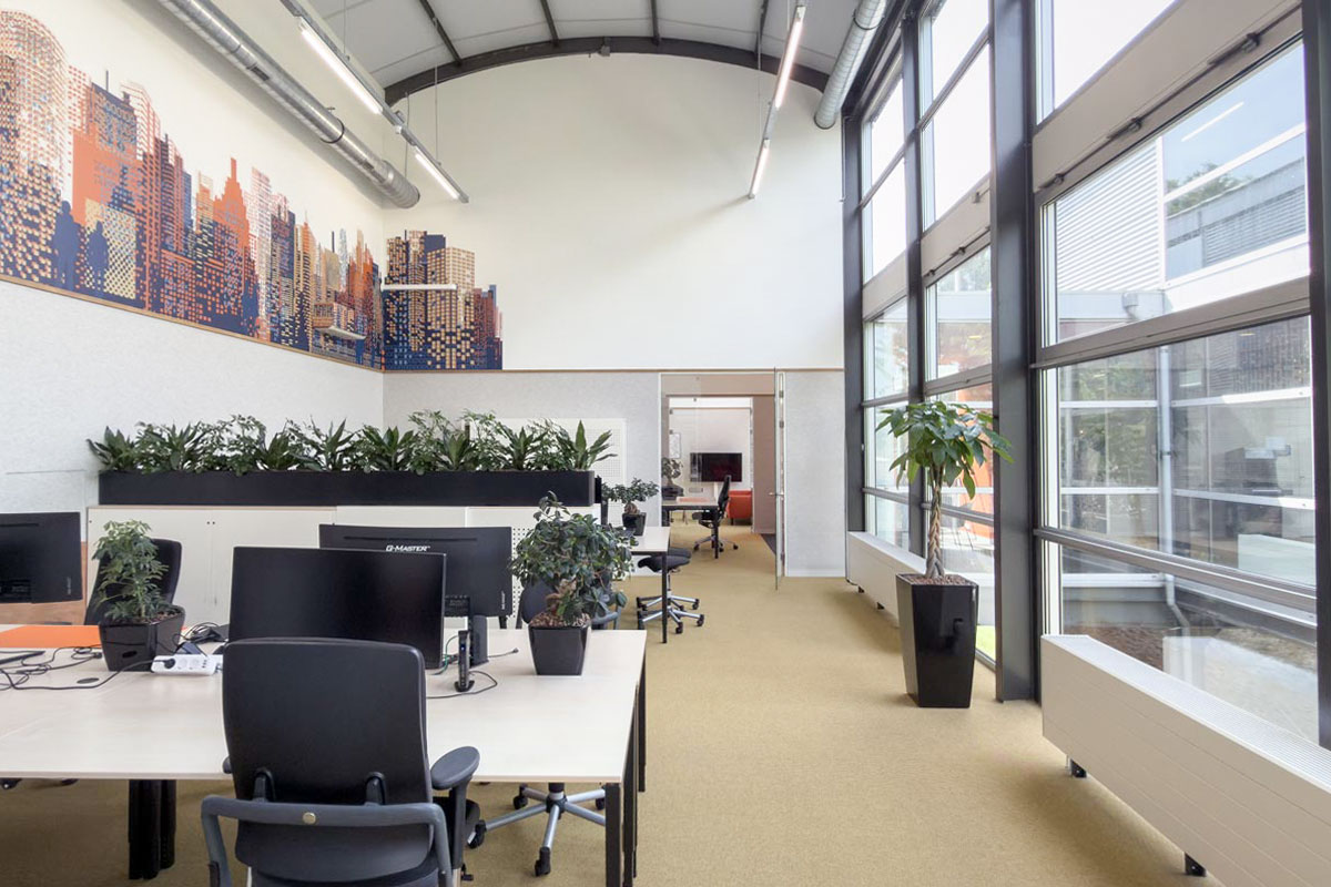 Werkplekken in kantoortuin in industrieel kantoorpand met Visuals aan de muur.