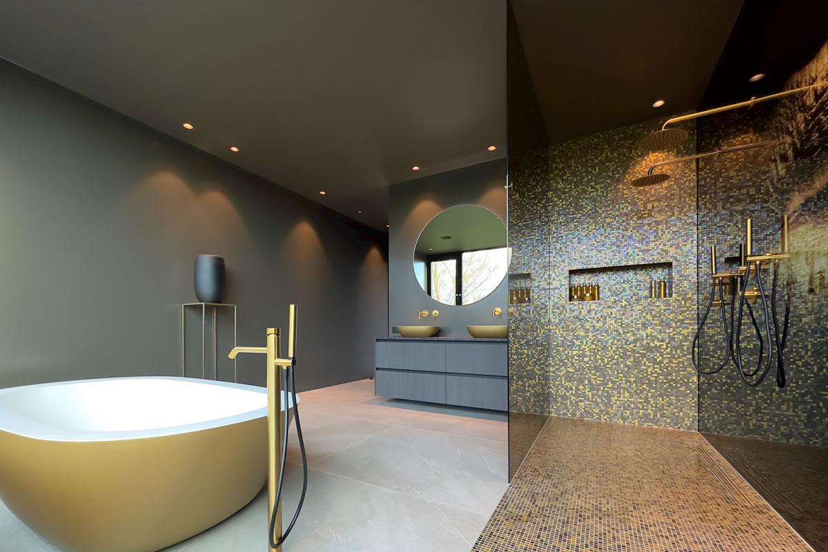 Luxe badkamer met gouden vrijstaand bad, dubbele wastafels, en mozaïektegels in wellness-stijl. Moderne inloopdouche met gouden kranen.