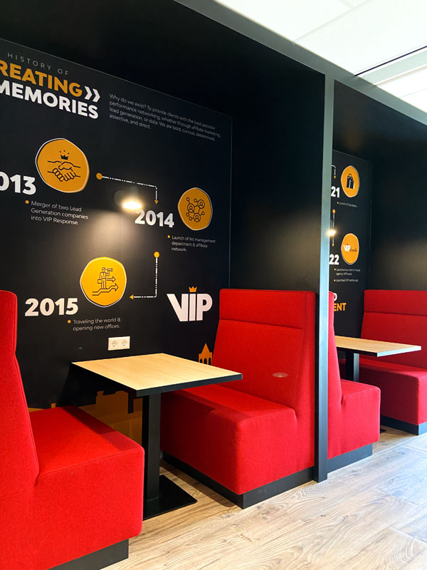 Kantoorinrichting VIP Response Utrecht, zithoek met rode bankjes en signing op zwarte wand