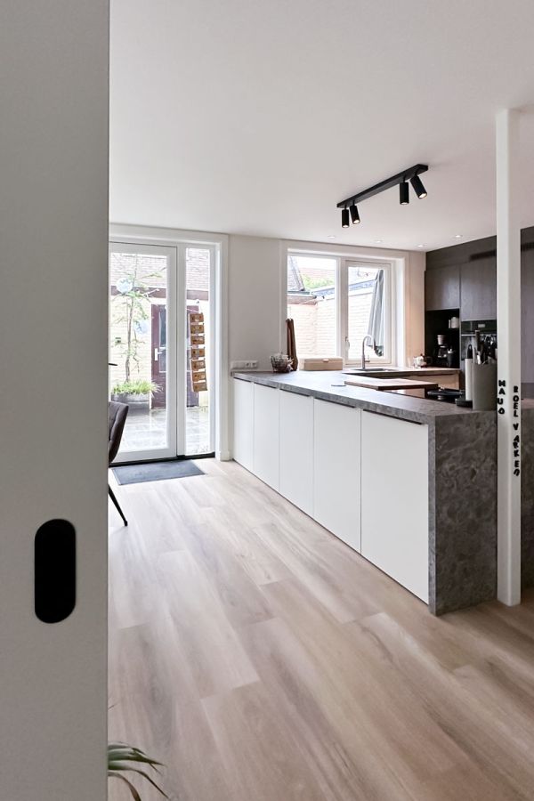 Lichte keuken in jaren 30 woning met grijs werkblad en glazen deuren naar tuin.