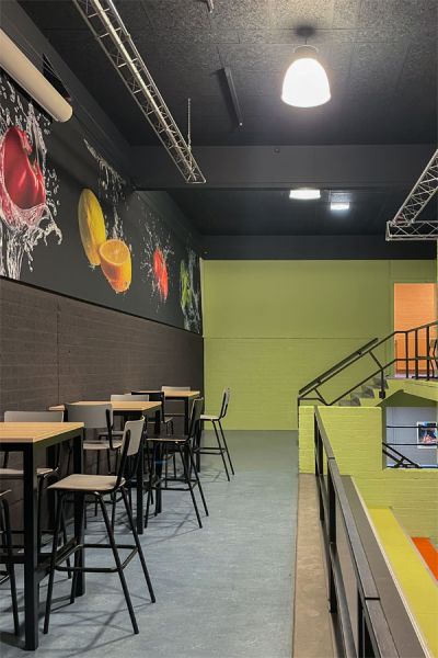 Schoolkantine met hoge tafels, visuals van fruit en kleurrijke wandpanelen