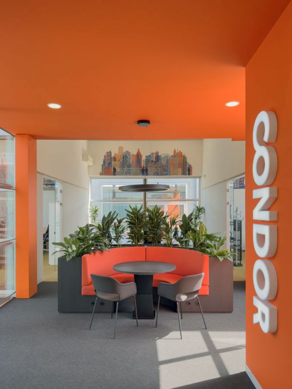 Entree Condor kantoor met oranje wand, verlicht logo en overlegplek op maat
