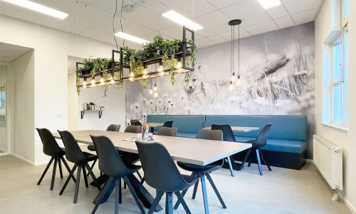 Schoolinrichting met leerplein, lange tafels en wandafbeelding in basisschool