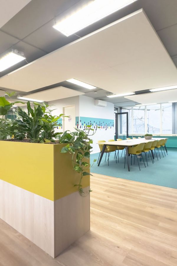 Gele plantenbakken met groen in de kantoorinrichting van Staij in Amsterdam, gecombineerd met frisse kleuren en een moderne vergaderruimte.