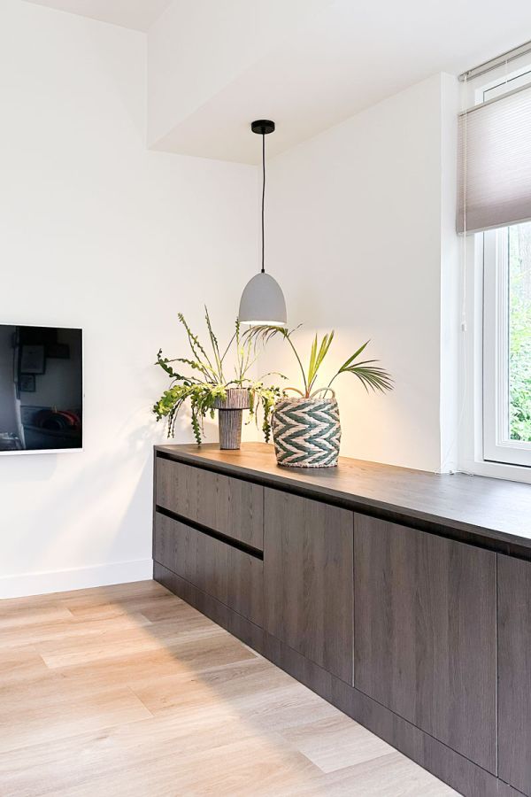 Kast op maat in de woonkamer met donkere houtprint en planten 