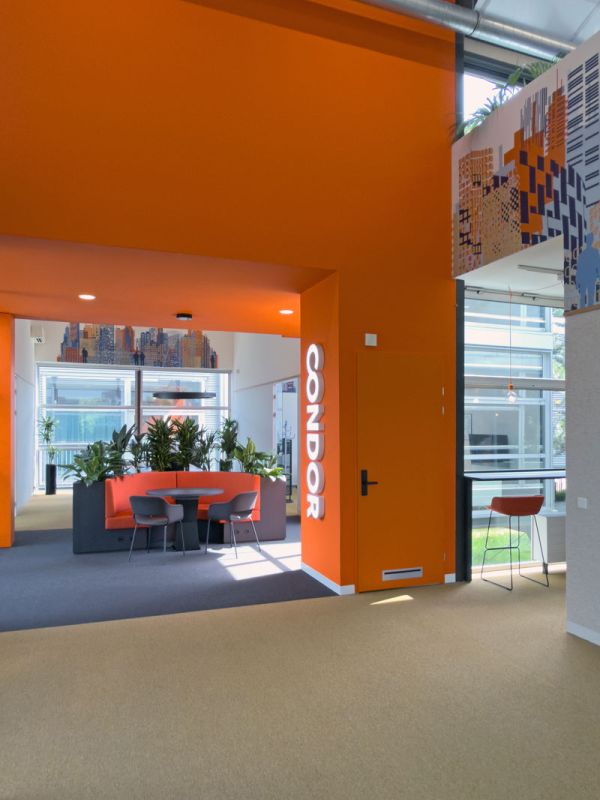 Kantoorpand in Amersfoort met ronde overlegplek met oranje muur, planten en verlicht logo.