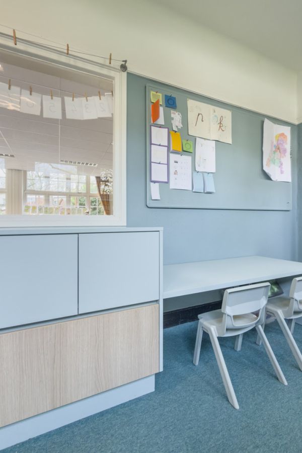 Werkplek in de gang voor kleuters en een kast op maat in lichtblauwe kleur met houtprint.