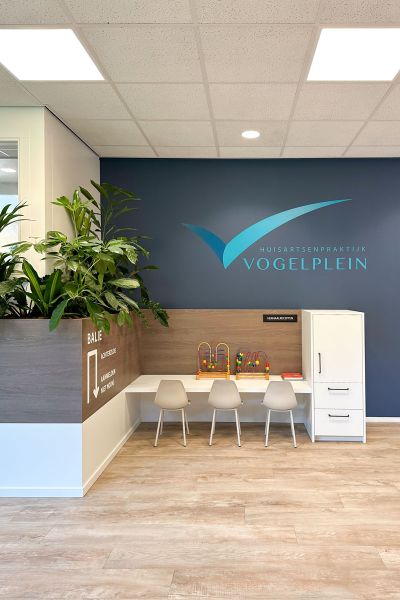 Wachtkamer met kinderhoek, balie, beplanting en rustige kleuren