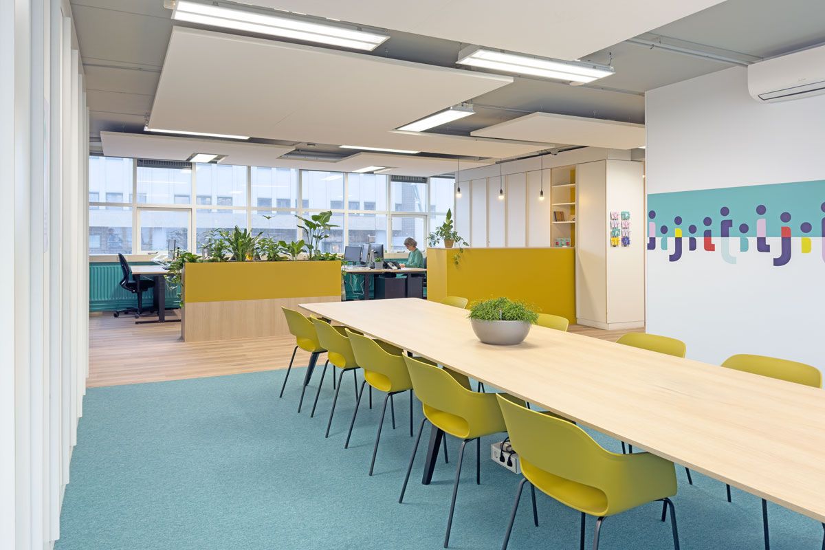 Moderne kantoorinrichting in Amsterdam met grafische prints in de huisstijl van Staij en een grote lunch- en vergadertafel.